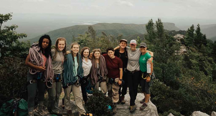 a group of students pose atop a summit in the blue ridge mountains on an outward bound course
